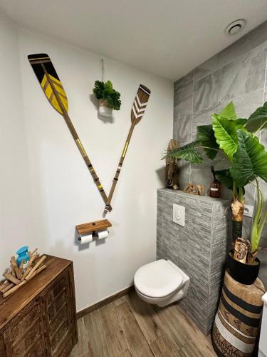 une salle de bain avec toilettes et deux pagaies au mur dans l'établissement VILLA FENG SHUI déco bali St Aygulf 3 chambres, à Saint-Aygulf