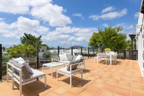 een patio met witte stoelen en tafels op een dak bij Spacious Private Villa up to 16 - Authentic Yaiza - Volcano, Timanfaya park, Bodega & South Beaches - Heated Pool - Game Room - Charcoal grill in Yaiza