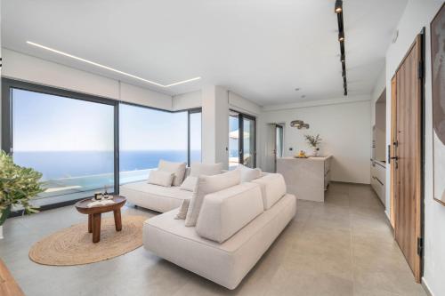 a living room with white furniture and large windows at Nimbus Villas in Kalamitsi