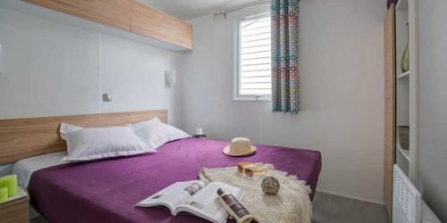 een slaapkamer met een paars bed met een hoed erop bij Camping 5 étoiles - Parc aquatique - eeiaid in Pénestin