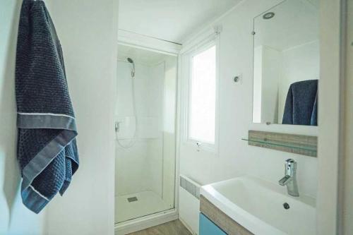 Un baño blanco con lavabo y ducha. en Camping 3 étoiles - Parc aquatique - eeibbf, en Fouesnant