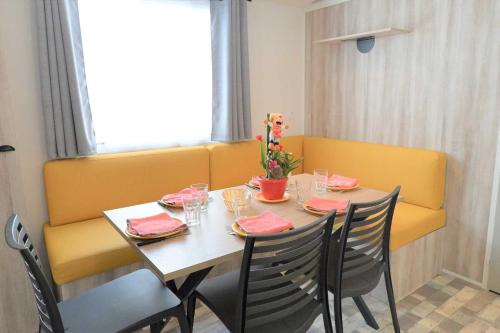 mesa de comedor con sillas y banco amarillo en Camping 4 étoiles - Parc aquatique - eeibci, en Le Bois-Plage-en-Ré