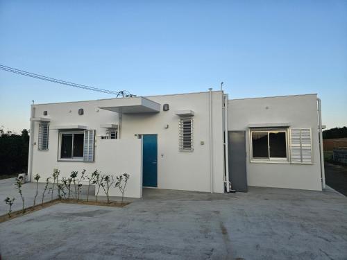 a white building with a blue door in a parking lot at Cozy Barn Ishigaki in Ishigaki Island