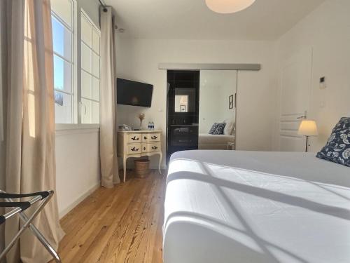 a white bedroom with a bed and a television at Domaine De Bonaveau - Privatisation Spa et Piscine in Barcelonne
