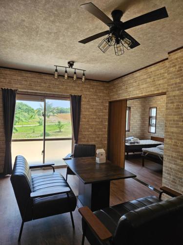 a living room with a couch and a ceiling fan at Cozy Barn Ishigaki in Ishigaki Island