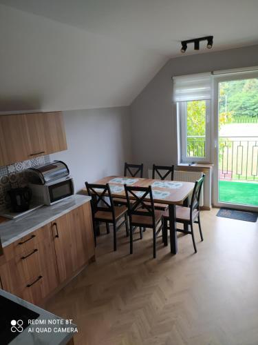 eine Küche und ein Esszimmer mit Tisch und Stühlen in der Unterkunft Domek NA SKRAJU WSI, APARTAMENTY in Górki Wielkie