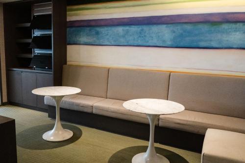 two tables in front of a couch with a painting at 塔木德酒店 台中火車站館 Talmud Hotel Taichung Station in Taichung