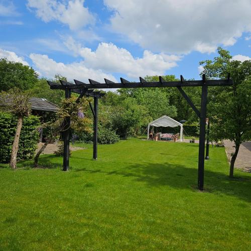 a wooden pergola in a field with a tent at Delicateske in Meppen