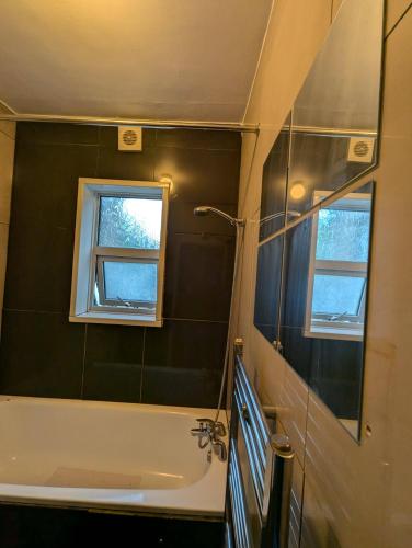 a bathroom with a bath tub and a window at 3B-10min City Airport Parking No Parties allowed in London