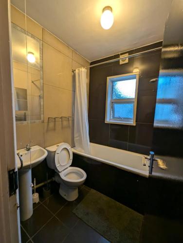a bathroom with a toilet and a tub and a sink at 3B-10min City Airport Parking No Parties allowed in London