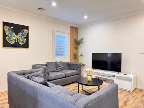 a living room with a couch and a butterfly on the wall at Blue Haven Retreat - Jordan Springs in Kingswood