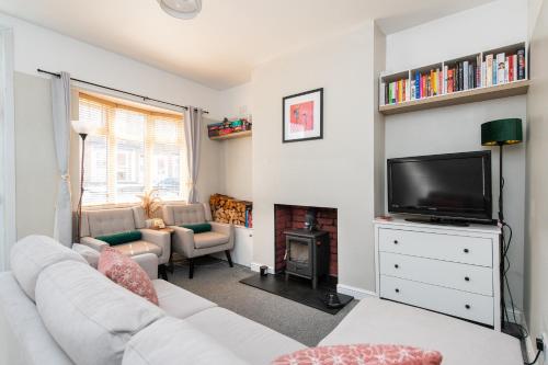 a living room with a white couch and a tv at Central 2 BR Cosy House in Rugby