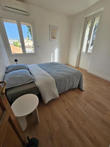 une chambre avec un lit et une table et deux fenêtres dans l'établissement Appartement vélodrome, à Marseille
