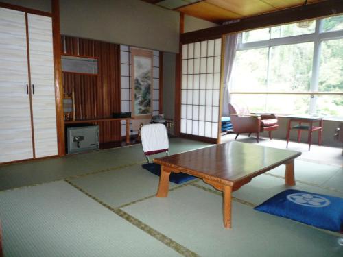 a living room with a wooden table and chairs at Takao Kanko Hotel in Kyoto