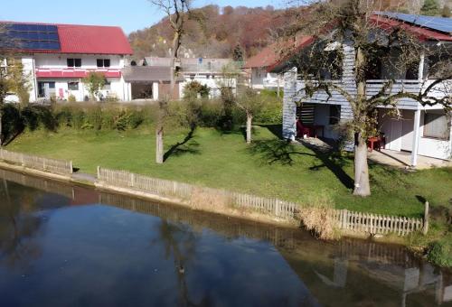 a view of a river with a house in the background at Ferienwohnung an der Lauter in Indelhausen