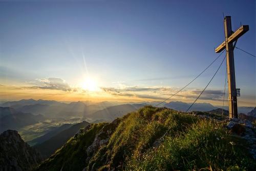 a cross on top of a mountain with the sunset at Sunside Apartment in Zell am Ziller