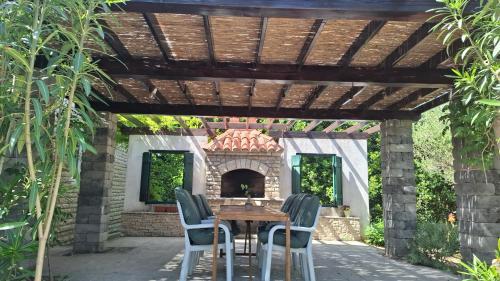 a patio with a wooden table and chairs under a pergola at Barbat 249 in Barbat na Rabu