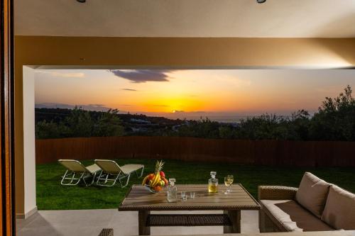 a patio with a table and chairs and a sunset at Olivia in Pigianos Kampos