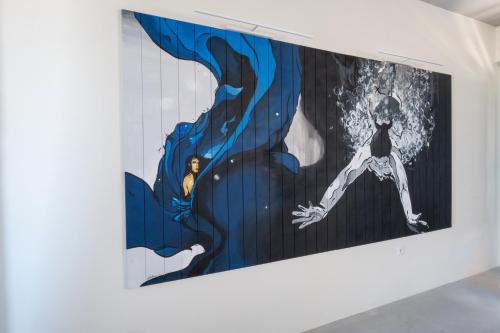 a painting on a wall in a room with a person in the background at IfestAu.4 Suites in Fira