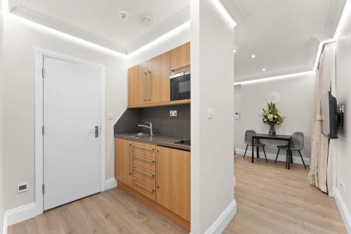a kitchen with white walls and wooden cabinets at Cleveland Residences Russell Square in London
