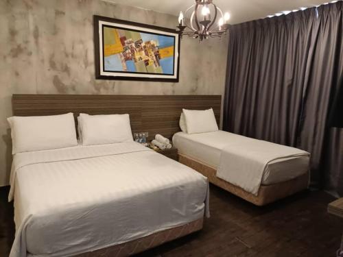 a hotel room with two beds and a chandelier at Raintree Boutique Hotel in Kajang