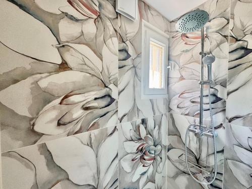 La salle de bains est pourvue d'une douche et de papier peint à fleurs. dans l'établissement Appartement avec jardin - Cap d'Agde, au Cap d'Agde