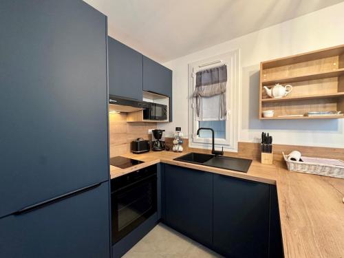 - une cuisine avec des armoires bleu foncé et un évier dans l'établissement Appartement avec jardin - Cap d'Agde, au Cap d'Agde
