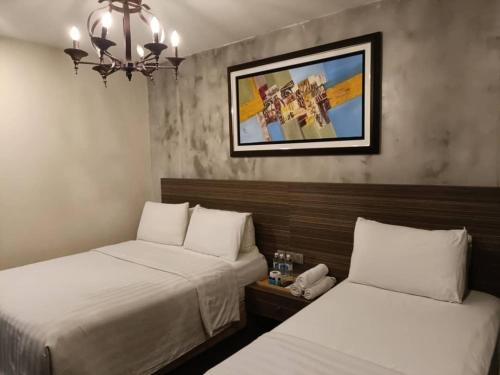 a hotel room with two beds and a picture on the wall at Raintree Boutique Hotel in Kajang