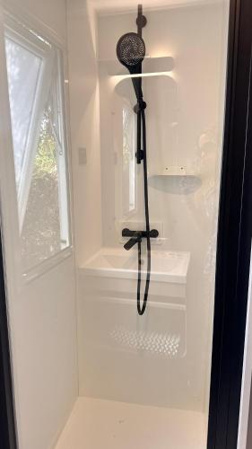 a white shower with a black brush in a room at Camping Villa Park Zambujeira do Mar in Zambujeira do Mar