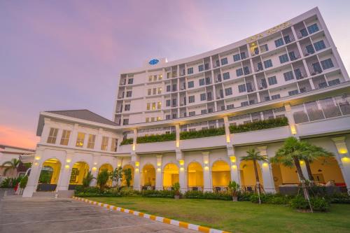 a large white building with palm trees in front of it at Vapa Hotel - SHA Extra Plus in Phuket Town