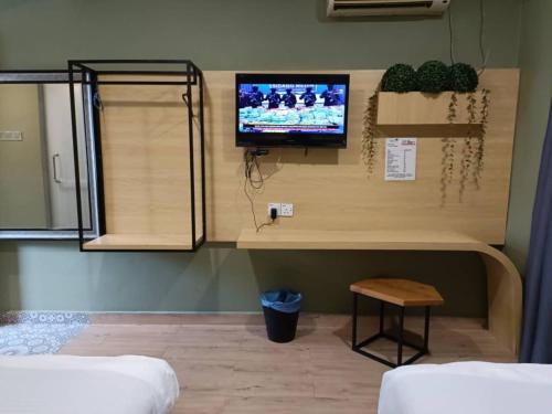 a room with a tv on a wall with a table at Raintree Boutique Hotel in Kajang