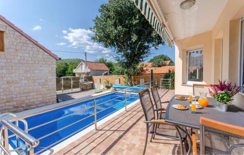 Un patio con mesa y sillas junto a una piscina. en Cozy Home In Primorski Dolac, en Primorski Dolac