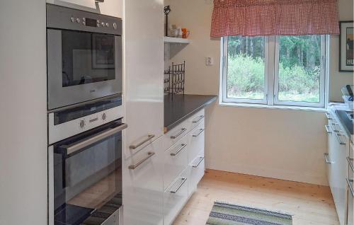 a kitchen with white appliances and two windows at Lovely Home In Rimforsa With Lake View in Rimforsa