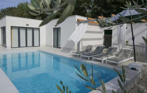 a swimming pool with lounge chairs next to a house at Gorgeous Home In Fazana in Fažana