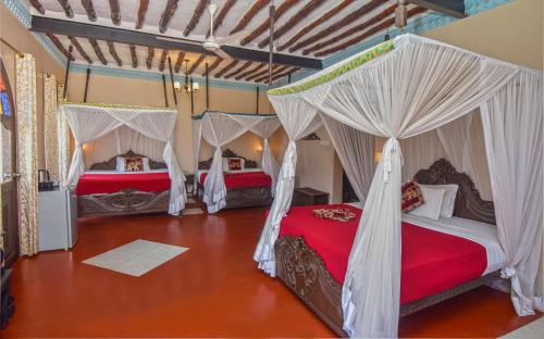 two beds in a room with white drapes at Tembo House Hotel in Zanzibar City