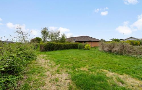 a grassy yard with a hedge and a house at Cozy Home In Årslev With Wifi in Årslev