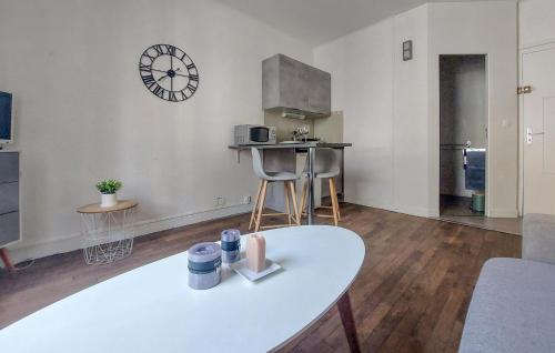 a living room with a table and a clock on the wall at Stunning Apartment In Saint-Malo in Saint Malo