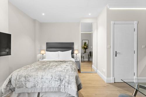a white bedroom with a bed and a table at Cleveland Residences Russell Square in London