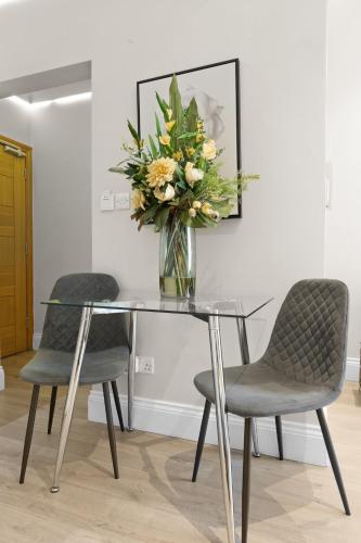 a glass table with two chairs and a vase of flowers at Cleveland Residences Russell Square in London