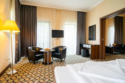 a hotel room with a bed and a table and chairs at Hotel Castello & Thermal Spa Siklós in Siklós