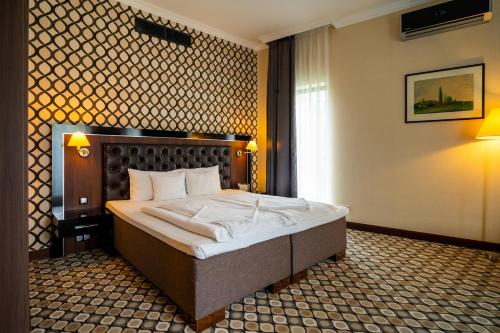 a bedroom with a large bed in a room at Hotel Castello & Thermal Spa Siklós in Siklós