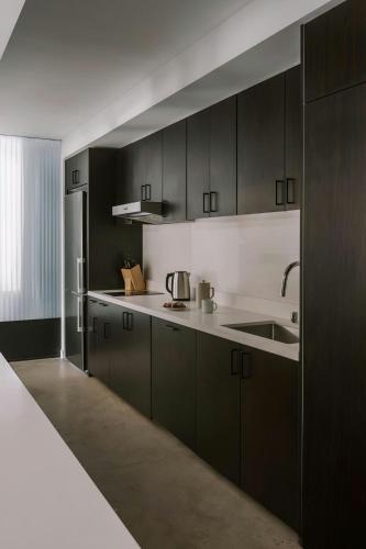 a kitchen with black cabinets and a sink at Sonder by Marriott Bonvoy The Winfield Apartments Downtown LA in Los Angeles