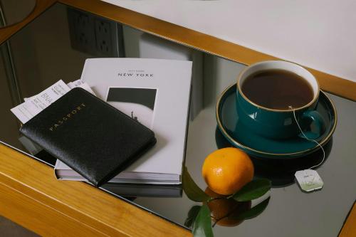 a book and a cup of coffee and an orange on a table at Henri on 24 Hotel Chelsea, Sonder by Marriott Bonvoy in New York