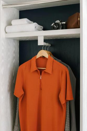 an orange shirt on a shelf in a closet at The Industrialist Hotel Gowanus Brooklyn, Sonder by Marriott Bonvoy in Brooklyn