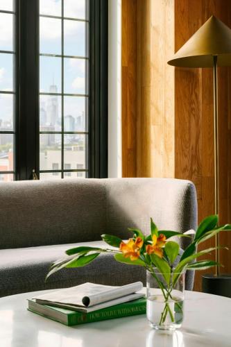 a vase of flowers on a table with a couch at The Industrialist Hotel Gowanus Brooklyn, Sonder by Marriott Bonvoy in Brooklyn