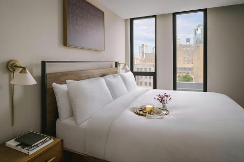 a bedroom with a white bed with a plate of flowers on it at Sonder by Marriott Bonvoy North Loop Green Apartments North Loop in Minneapolis