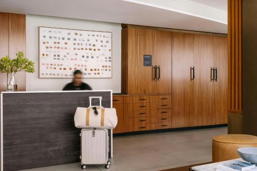 a man standing behind a counter with a suitcase in a lobby at Duane Street Hotel Tribeca, Sonder by Marriott Bonvoy in New York