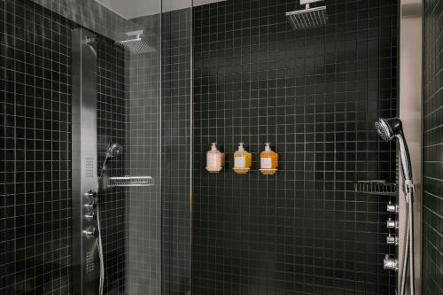 a green tiled shower with three bottles of soap at Duane Street Hotel Tribeca, Sonder by Marriott Bonvoy in New York