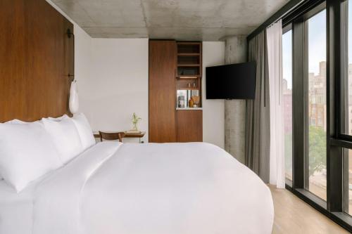 a bedroom with a white bed and a large window at The Merchant Hotel Lower East Side, Sonder by Marriott Bonvoy in New York