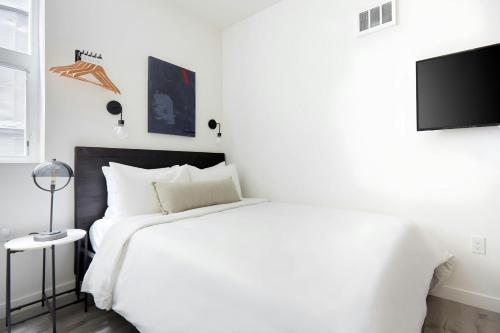 a white bedroom with a large bed and a tv at The Boylston Hotel Capitol Hill, Sonder by Marriott Bonvoy in Seattle
